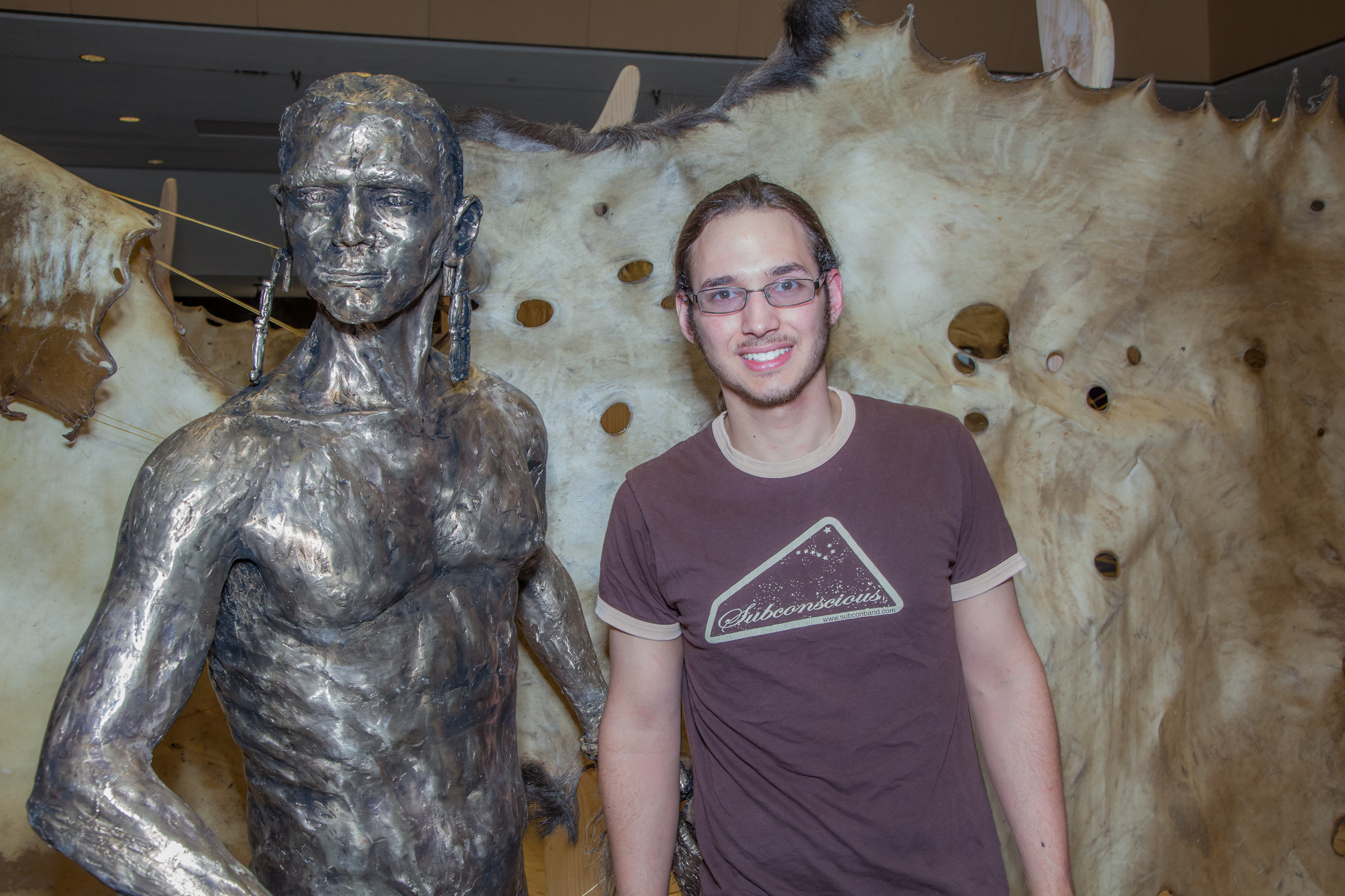 Senior art major Joel Isaak stands next to life-sized bronze sculpture he made as part of his senior thesis project during its display in the Great Hall. | UAF Photo by Todd Paris