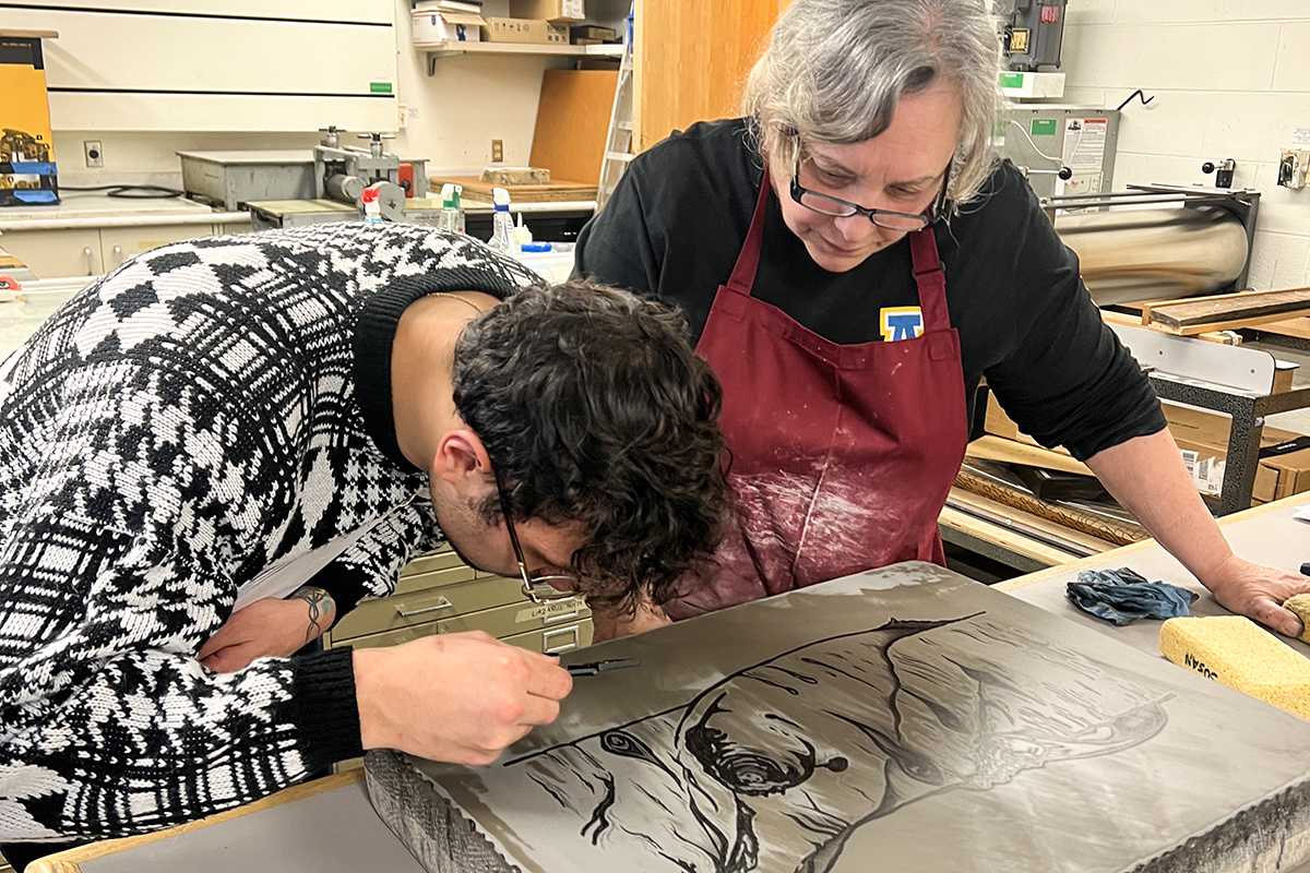 Two students examine a litho stone in the printmaking studio