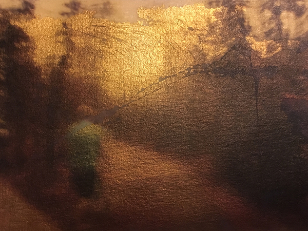 A man pushes a stroller down a path through the woods, gold metal foil showing through the light areas of the image
