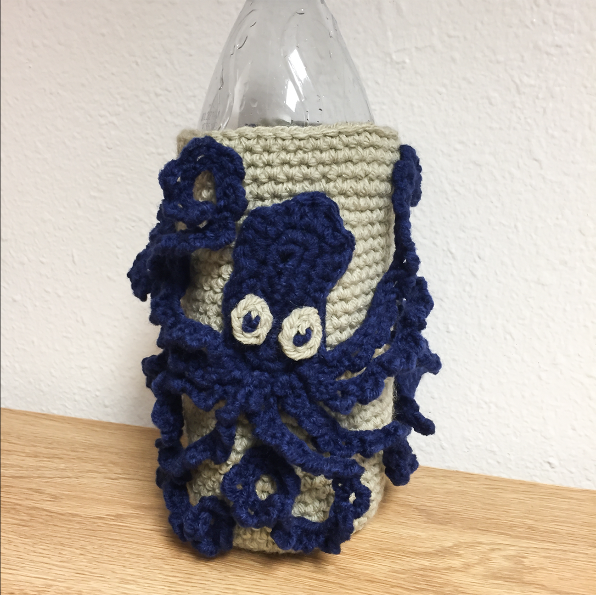 Knit reinterpretation of the octopus flask. A blur octopus on tan yarn wrapped around a water bottle.