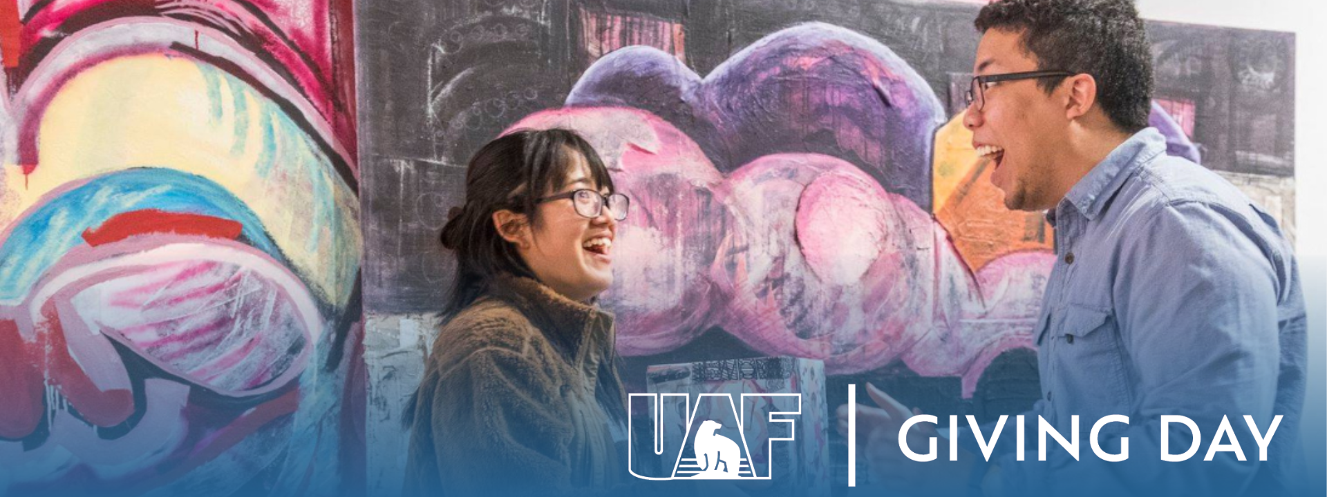 Art students Arisa Sasaki and Devante Owens in the UAF Art Gallery with a UAF Giving Day blue gradient banner overlaid on top.
