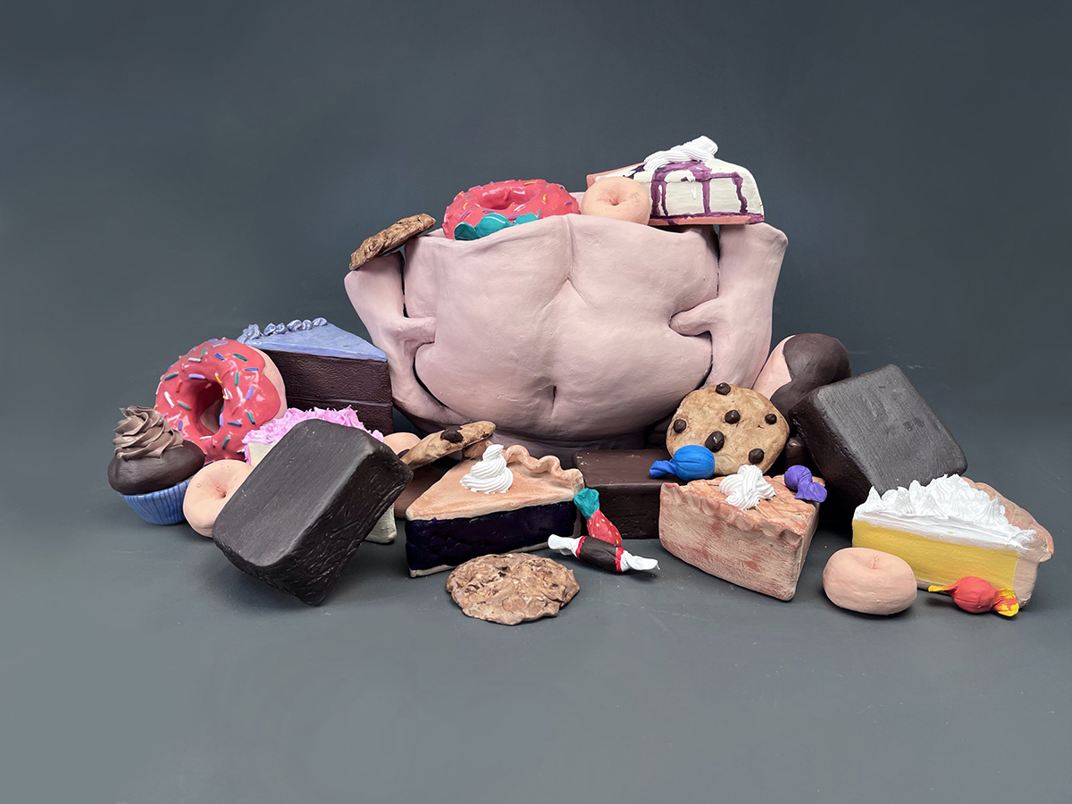 Ceramic torso surrounded by ceramic desserts