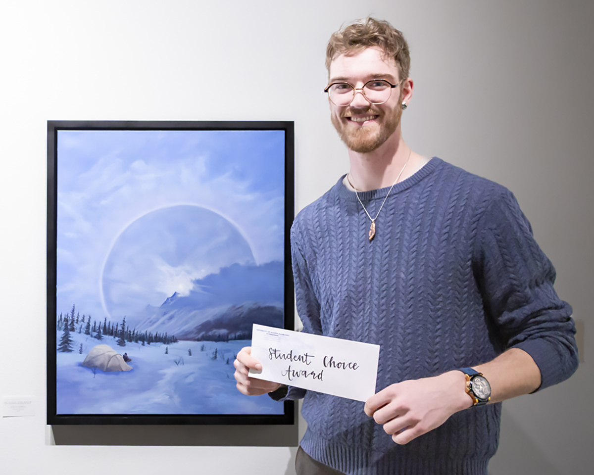 Fin Ludwig poses with his oil on canvas work, Be Still and Know, the Student Choice Award winner in the spring 2025 student juried exhibition.