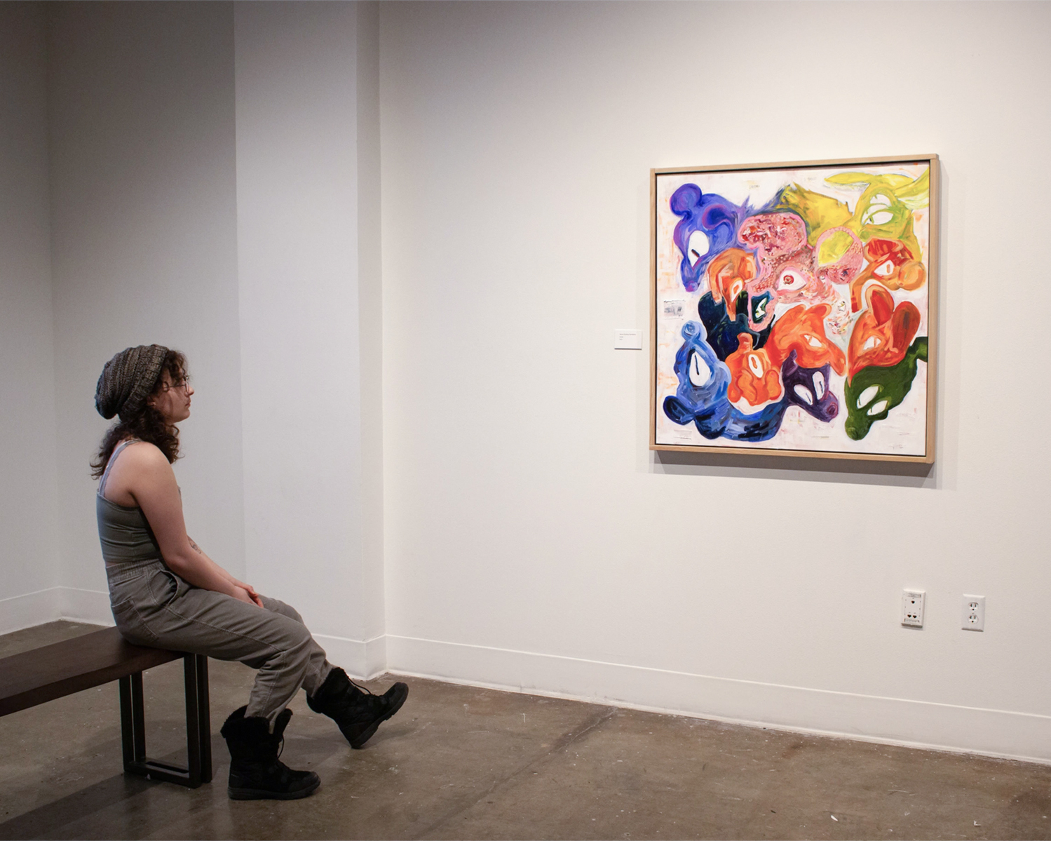 Chana Stern in UAF Art Gallery with her painting "Never-Ending Familiarity," part of her 2024 BFA thesis exhibition, Pilgrimage of the Revenant. Photo courtesy of Stern