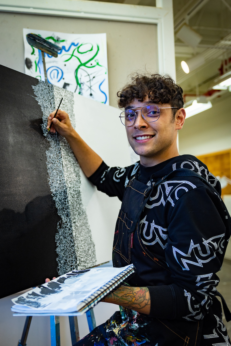 UAF Senior Kyle Augustines paints his thesis project in the painting studio of the Fine Arts Building. (UAF Photo by Leif Van Cise)