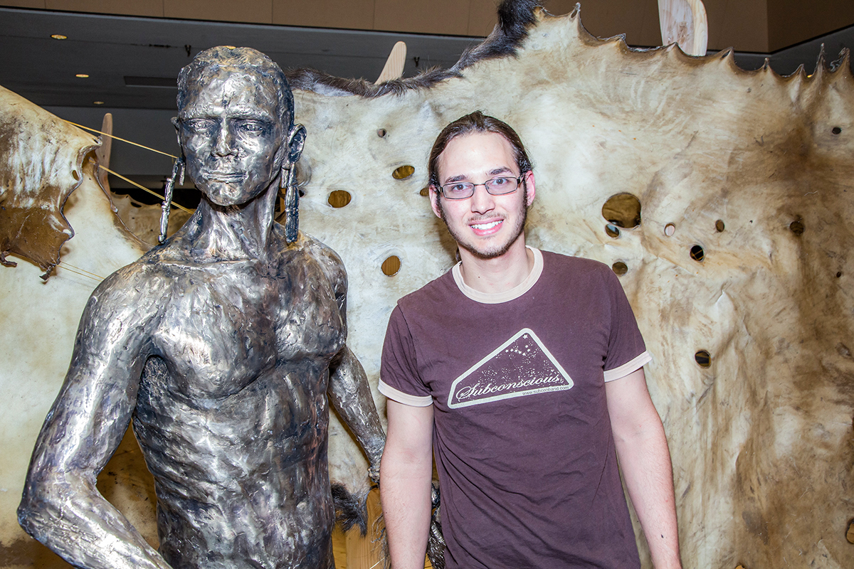 Art major Joel Isaak stands next to life-sized bronze sculpture he made as part of his senior thesis project during its display in the Great Hall. UAF Photo by Todd Paris