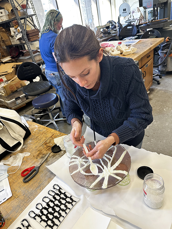 Sarah Dexter prepares a fused glass piece for the kiln. The process includes multiple firings, each one shaping the glass bit by bit into its final form. Photo courtesy of Dexter