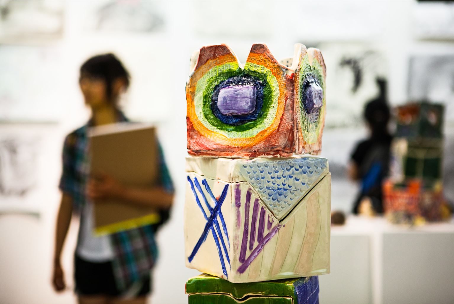A colorful block sculpture sits in the foreground of the Visual Arts Academy end of the season art show