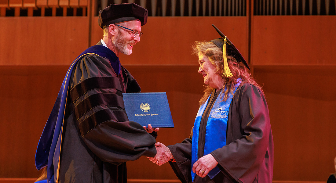UAF Chancellor Dan White bestows emeritus status on Michele Stalder, former dean of the Community and Technical College, during UAF's 101st commencement ceremonies May 5 in the Davis Concert Hall.