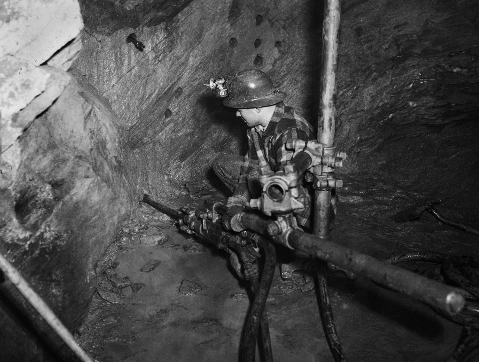 Students in the university’s mining program labor in the model mine operation, which the university established early in its history to give students practical experience. At top, a student in the training adit, the university’s mine under campus, guides a drill into the rock to make a hole for an explosive charge. Earl Beistline Collection, Accession number 1985-093-616, Archives, Alaska and Polar Regions Collections, Rasmuson Library, University of Alaska Fairbanks