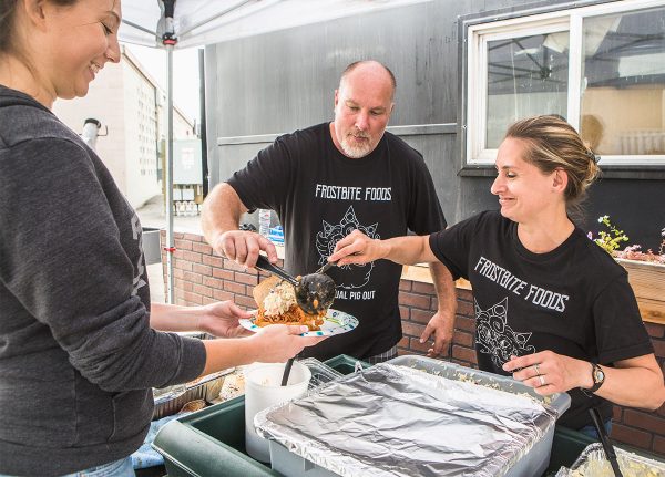 Marshal James and Monique Love, owners of Frostbite Foods, dish up food for Isabella Steward during the restaurant’s first Pig Out event July 15. James and Love opened the Fairbanks restaurant, located near the Gavora Mall, after taking Cooperative Extension Service courses and consulting with an Extension technician. Their family-friendly Pig Out event offered smoked pork, beef brisket, baked beans, potato salad and coleslaw, along with games, prizes and an eating contest. UAF photo by JR Ancheta.