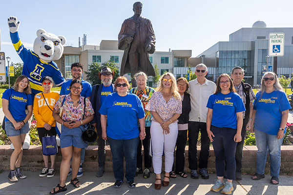 UAF alumni and staff gather for the campus tour during Nanook Rendezvous 2025. Back row, from left, are Nook, Kyle Agustines ’24, William Zybach ’81, Eleanor Smith ’75, Mary Donaldson, Wayne Donaldson ’80 and Robert Seitz ’68. Front row, from left, are UAF student assistant Keely Vatcher; Gwenetta Johnson ’96, ’99; Ray Alda ’21; Valerie Demming ’75, ’84; Rhonda Widener ’01; UAF alumni relations storytelling manager Katie Straub; and Judy Dellinger ’93.