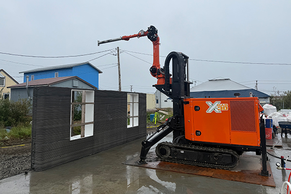A robotic 3D printer constructs the first wall of a 1,200-square-foot experimental concrete house in Nome in August 2025. Photo courtesy of Nima Farzadnia.
