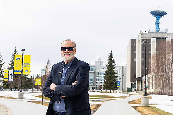 John Davies visits the Arctic Research Park on the Fairbanks campus in April 2026. As a seismologist, he worked and studied for many years at the Geophysical Institute, located in the Elvey Building (with the blue satellite dish). 