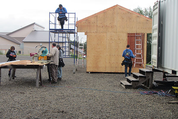 Construction trades students working outdoors on a wooden building structure