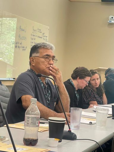 Four people at a conference table look to the right.