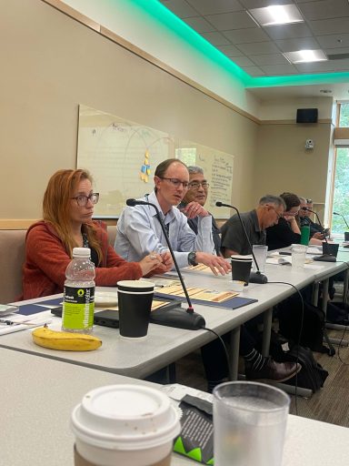 A group sits at a conference table and looks to the right.