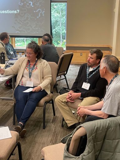 A group sits in a circle in a conference room.