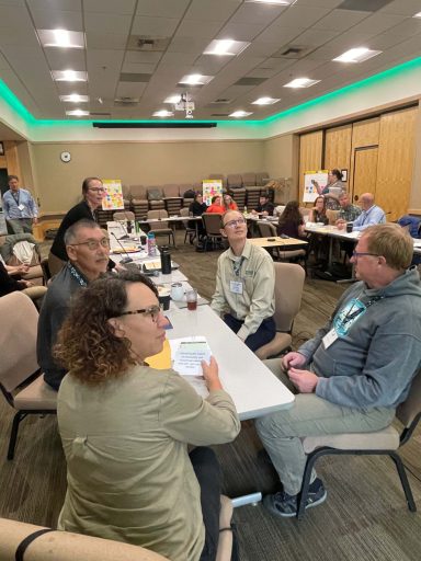 A group sitting at a conference table looks out of frame to the right.