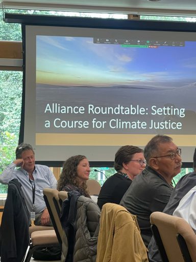 Four people at a conference table look to the right.