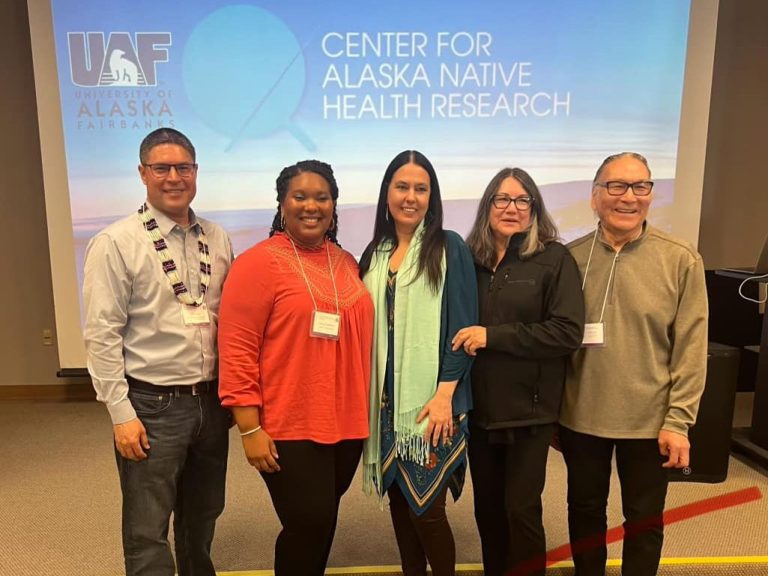Taa'ąįį Peter, Hannah Robinson, Stacy Rasmus, Cyndi Nation, and Aya'qulluk Chaliak posing for a picture at the presentation.