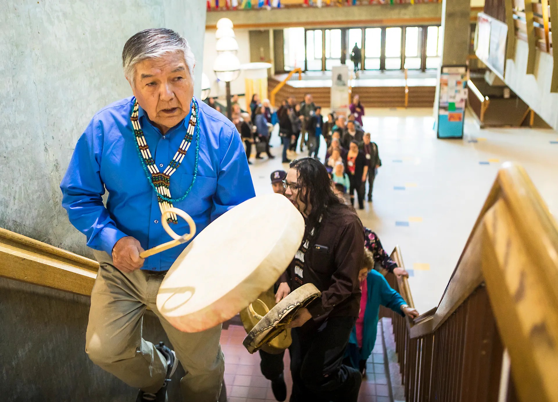 Elder playing a drum walking up the stairs