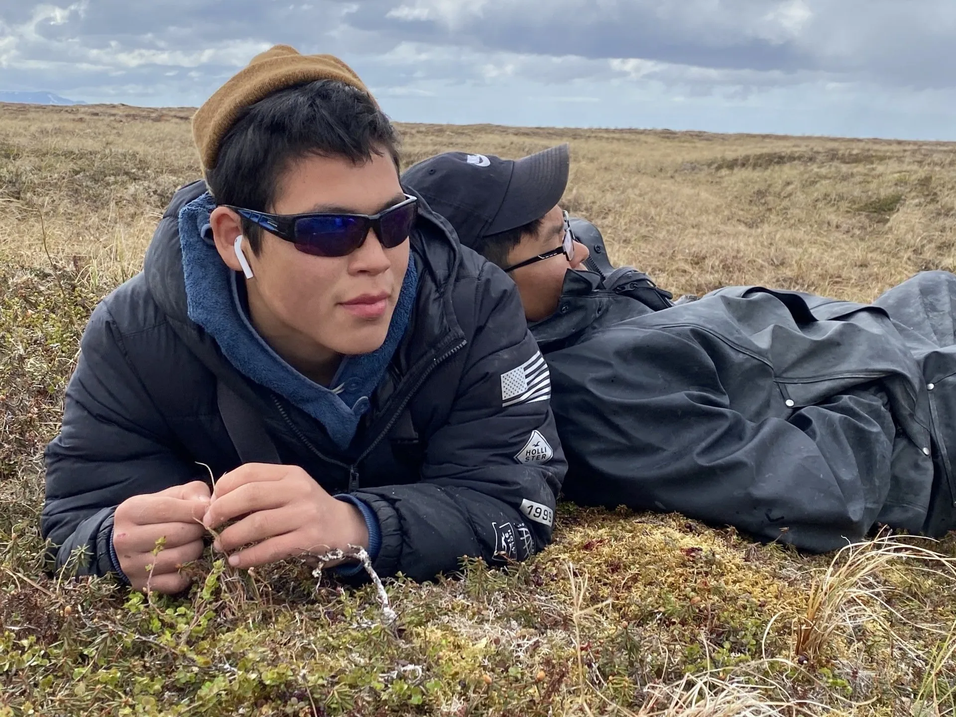 Two people lie down in a field and look into the distance