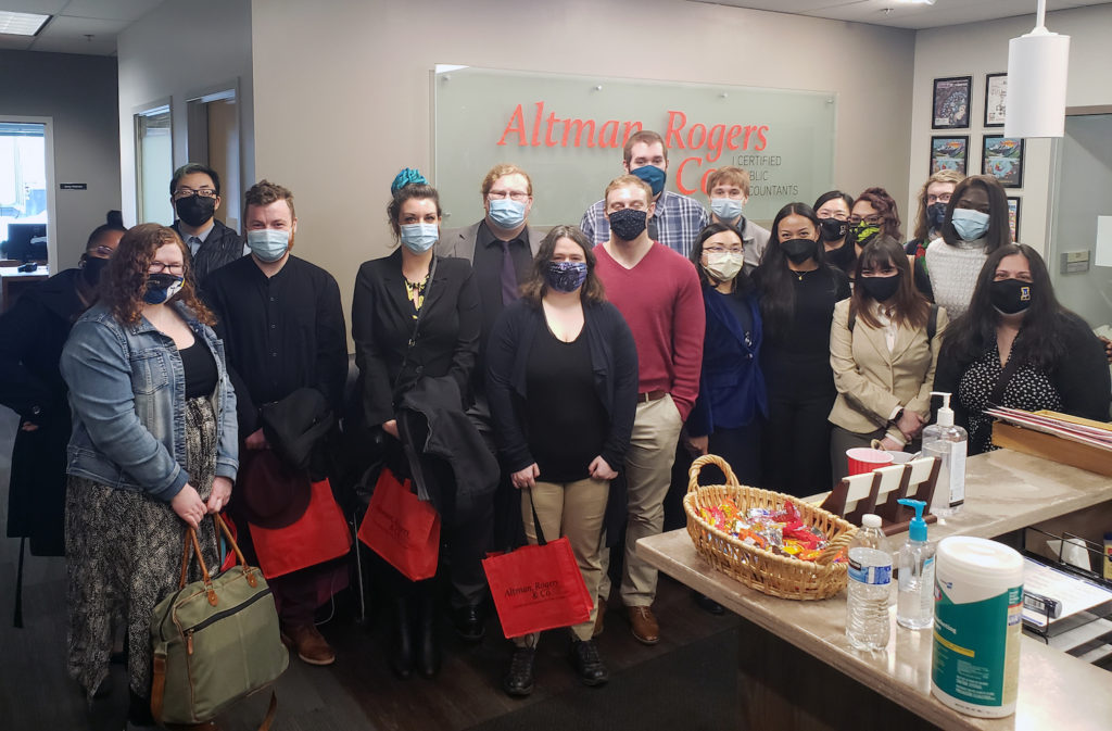 students wear masks holding red gift bags in the Altman Rogers & Co front lobby