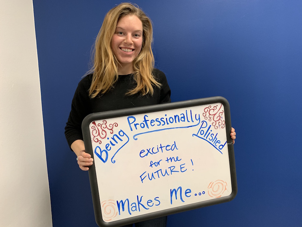 Student stands with sign: Being professionally polished makes me excited for the future!