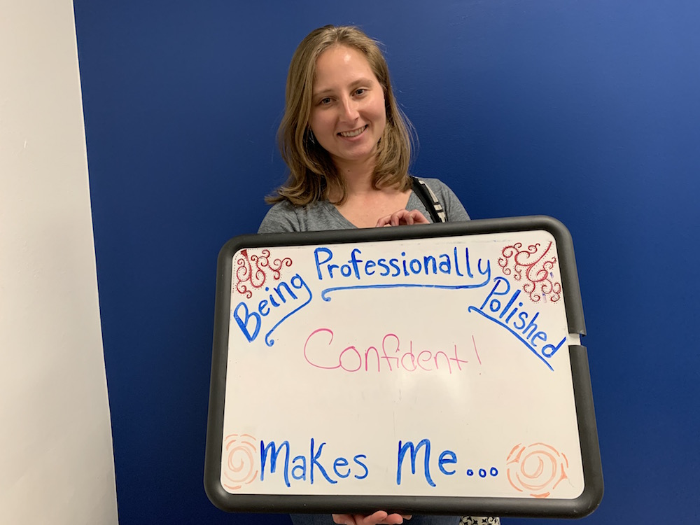 Student stands with sign: Being professionally polished makes me confident!