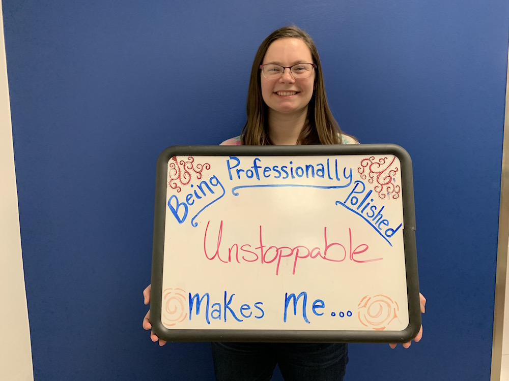 Student stands with sign: Being professionally polished makes me unstoppable