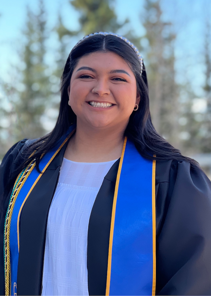woman with black hair smiles wearing gradation regalia