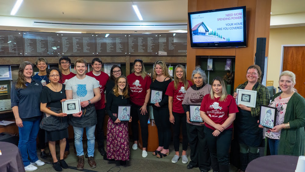 The SOM student team poses with the Roast and Boast partners, pictured with their gifts from artists Arisa Sasaki and Taylor Parsons. 