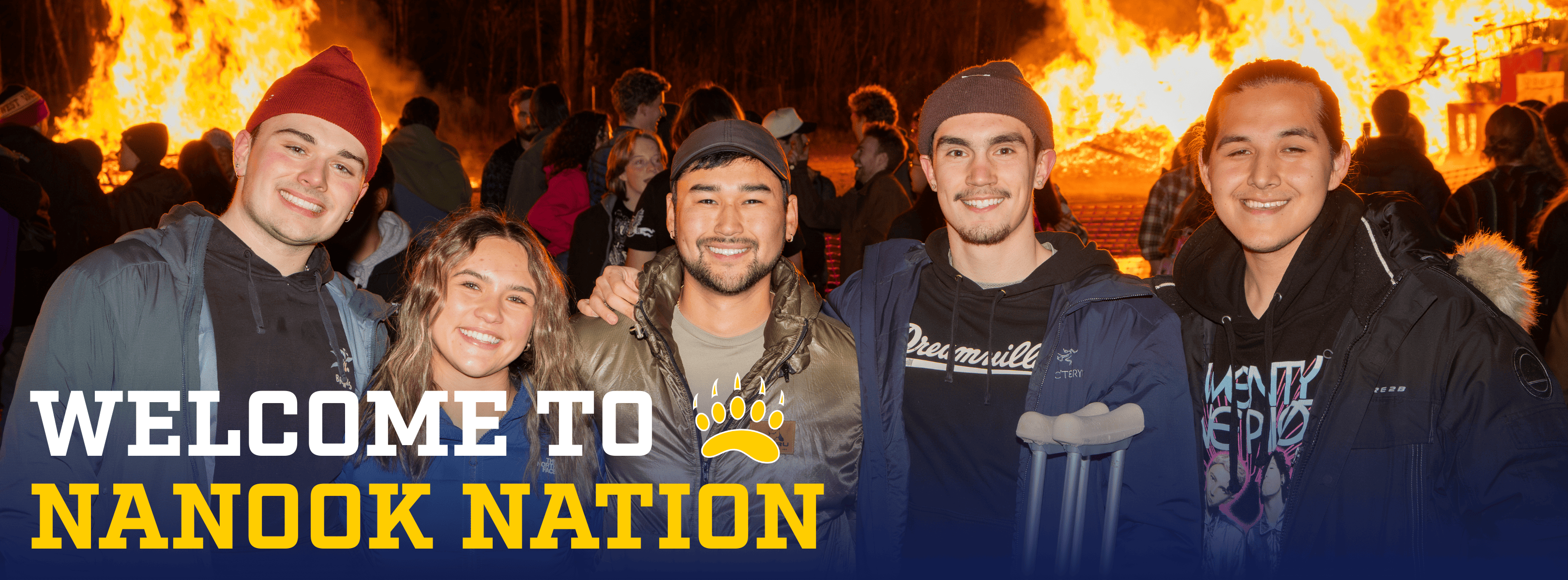 five students stand in front of bonfire