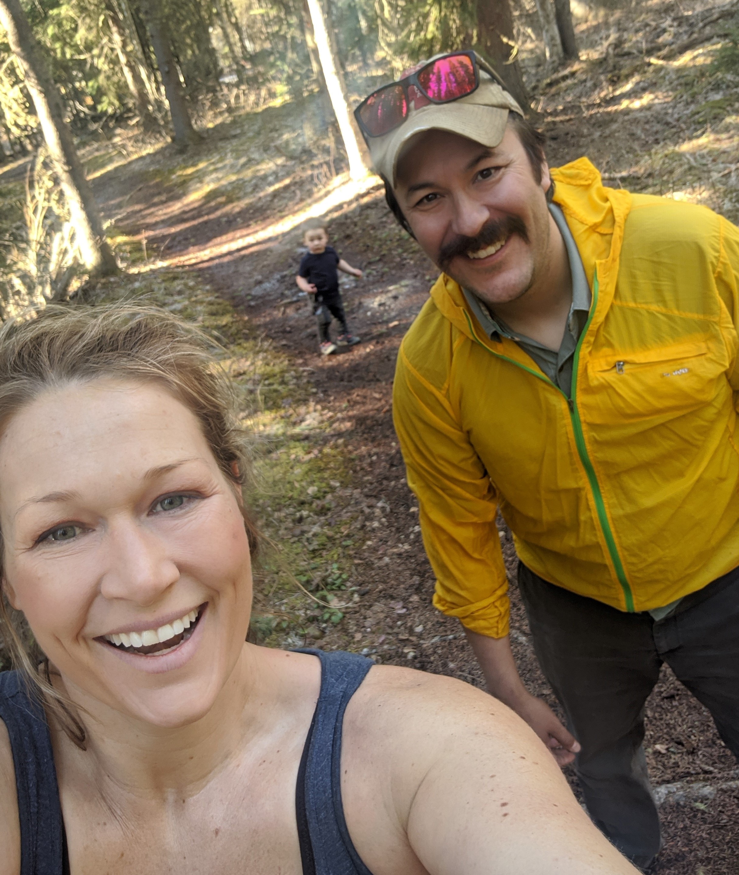 Parents and toddler hiking through a forest on a sunny day