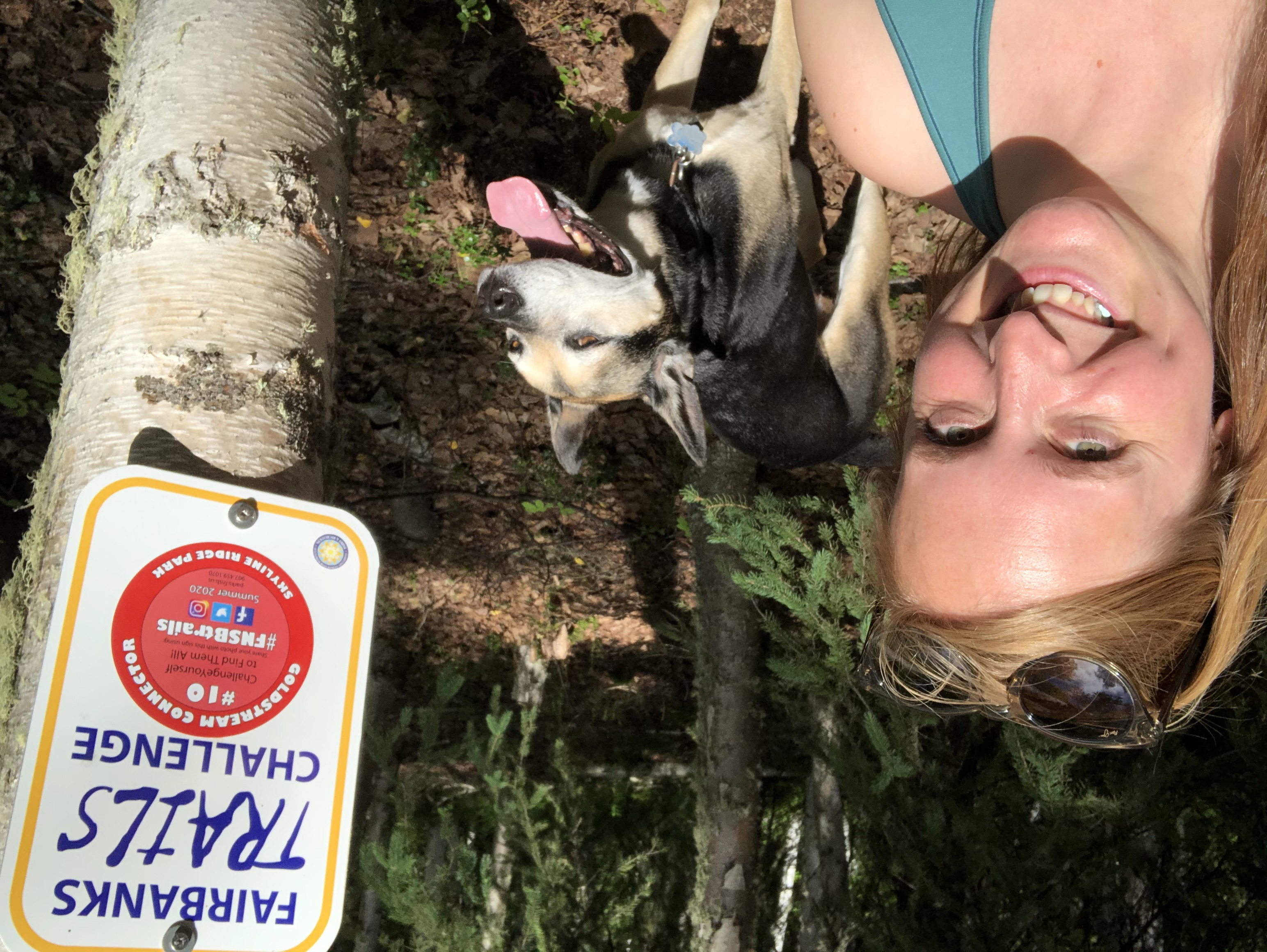 Amanda Langhorst takes selfie with dog in front of "Fairbanks TRAILS challenge" sign