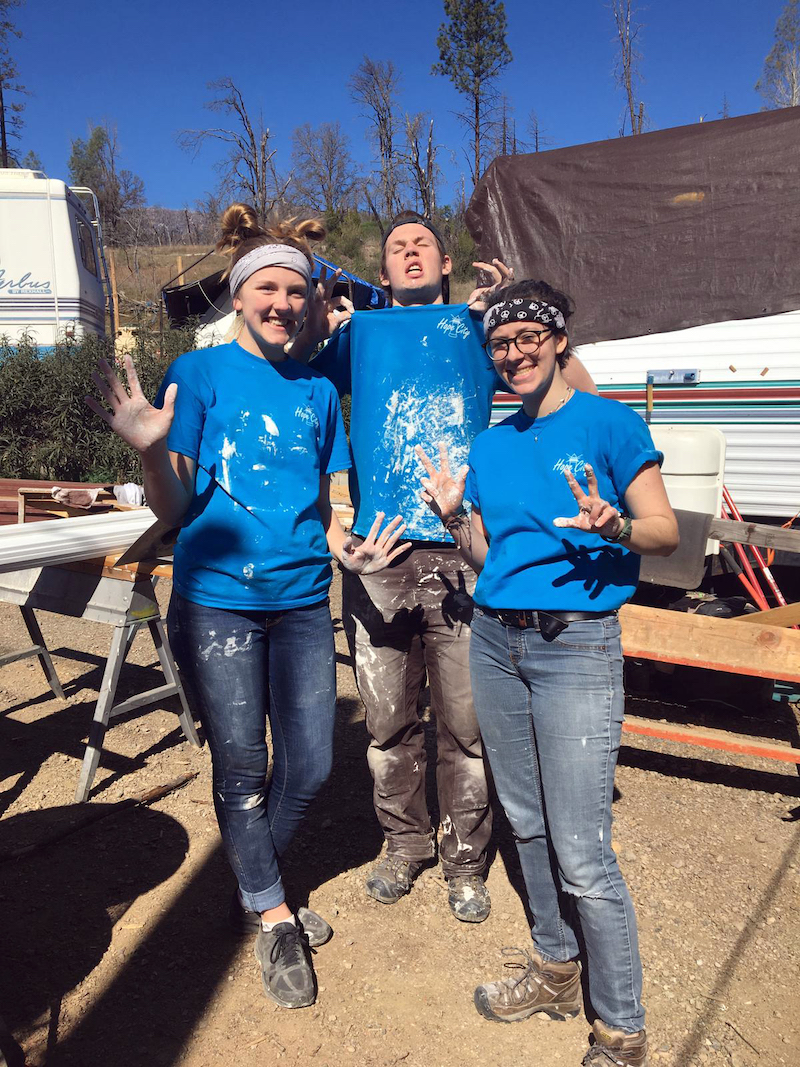 three students pose for photo during paint project