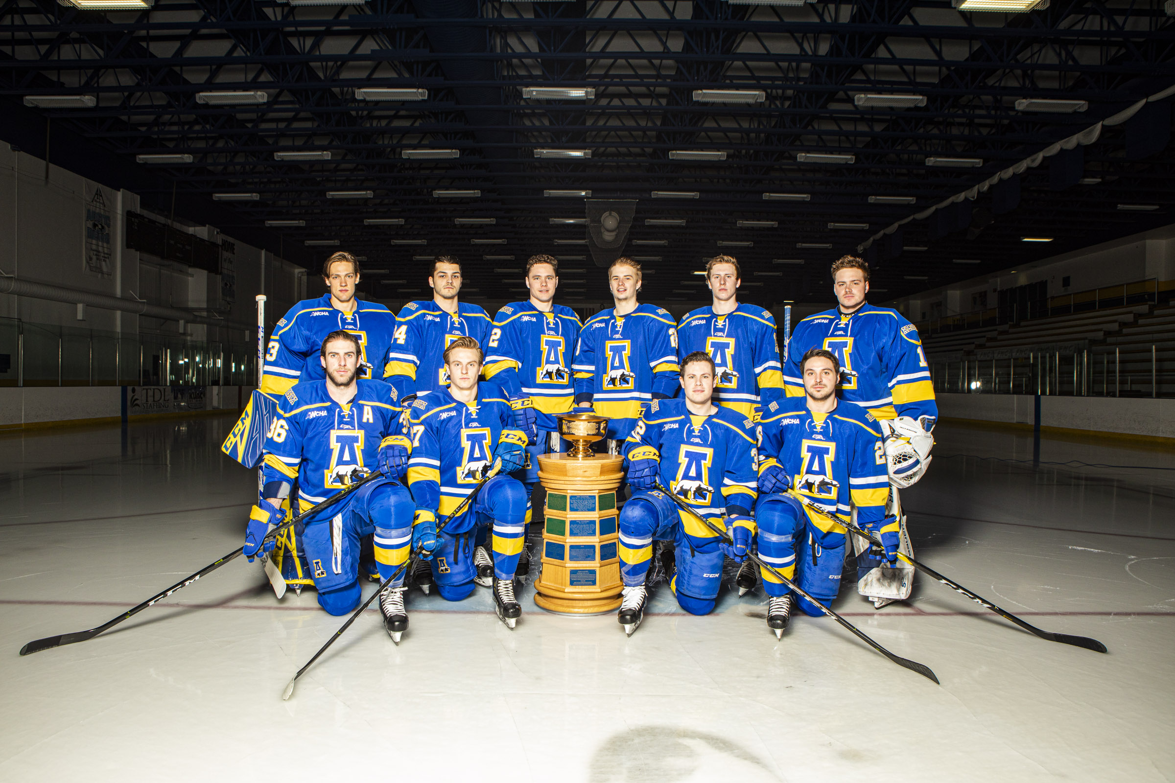 hockey team stands in uniform on ice with trophy
