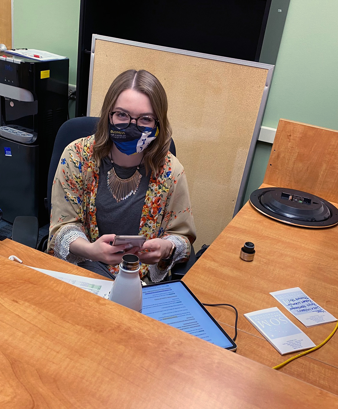 student works in office on phone and tablet