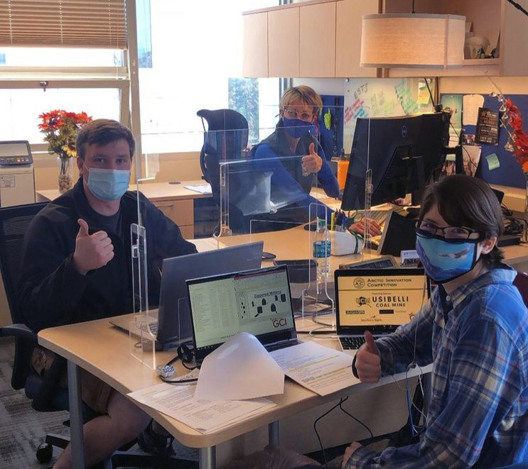 production team works on laptops wearing masks
