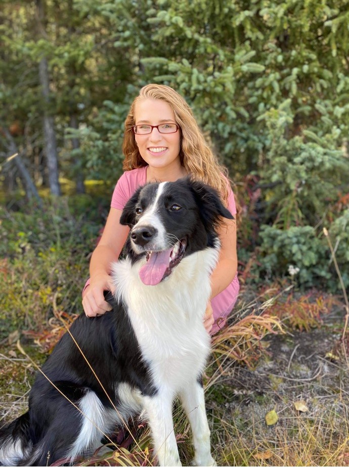 girl poses with her dog in woodland area