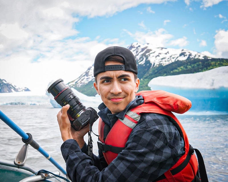 Man on boat at a glacier smiling with his camera