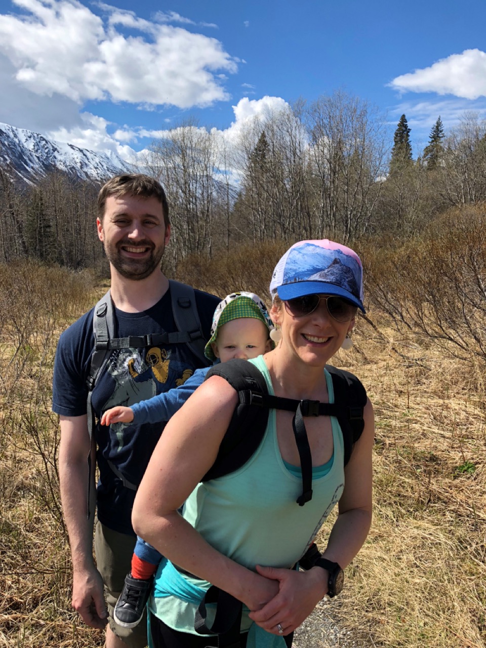 mom and dad smile with baby girl while hiking