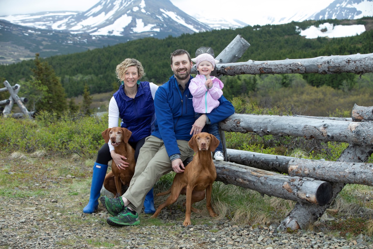 wife, husband, baby girl, and two dogs pose for outdoor family portrait
