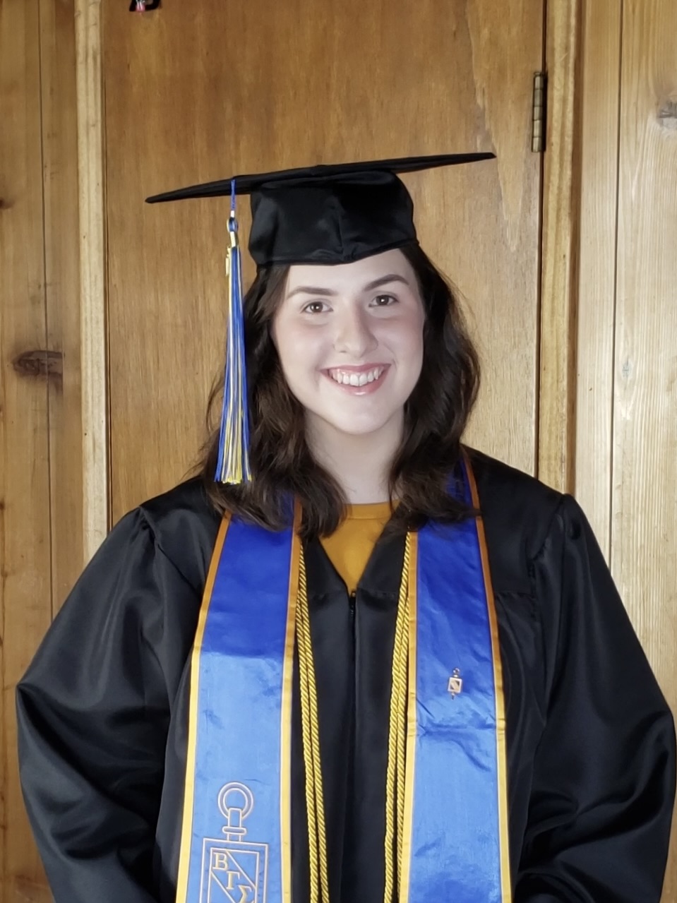 portrait of woman in university graduation cap, gown, and sash