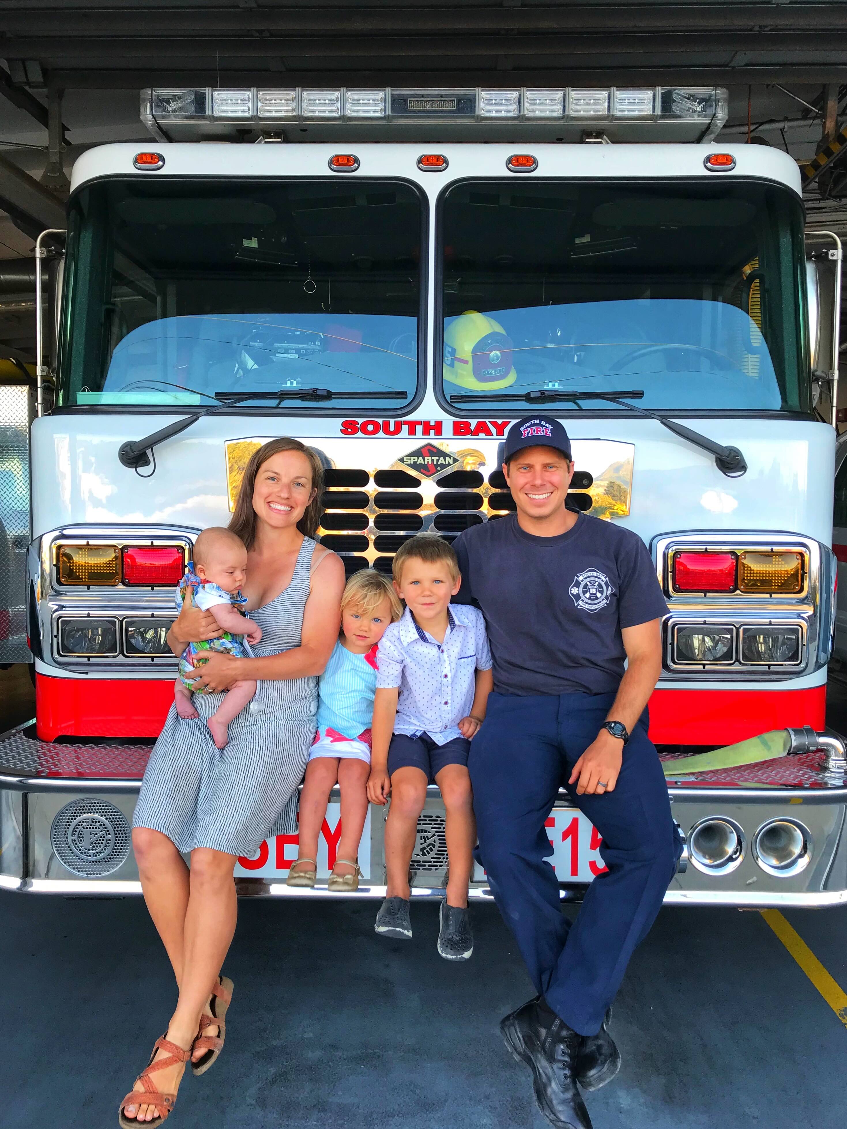 firefighter sits with wife and three kids on firetruck