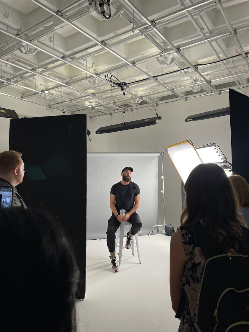 man sits on stool posing for a headshot in the studio