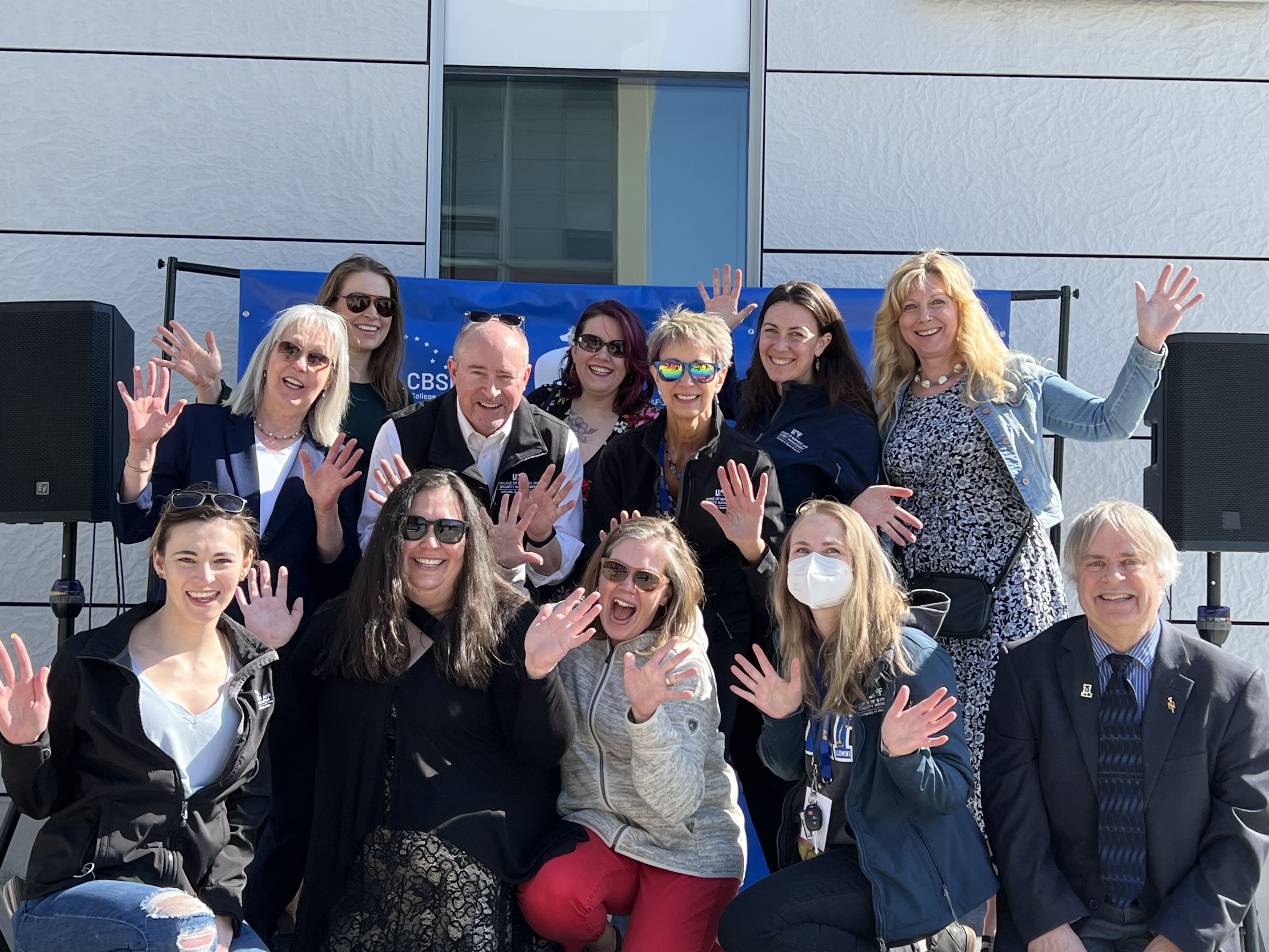 twelve people smile for picture holding all ten fingers up