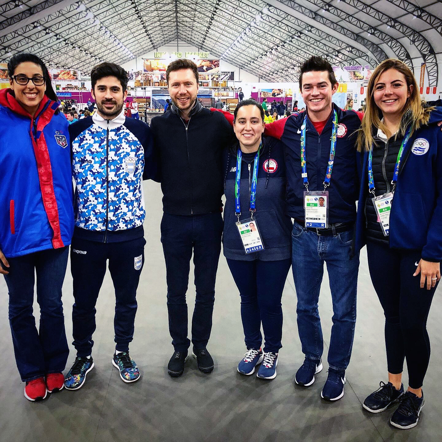 six friends stand together smiling for photo in sport clothing and badges at conference