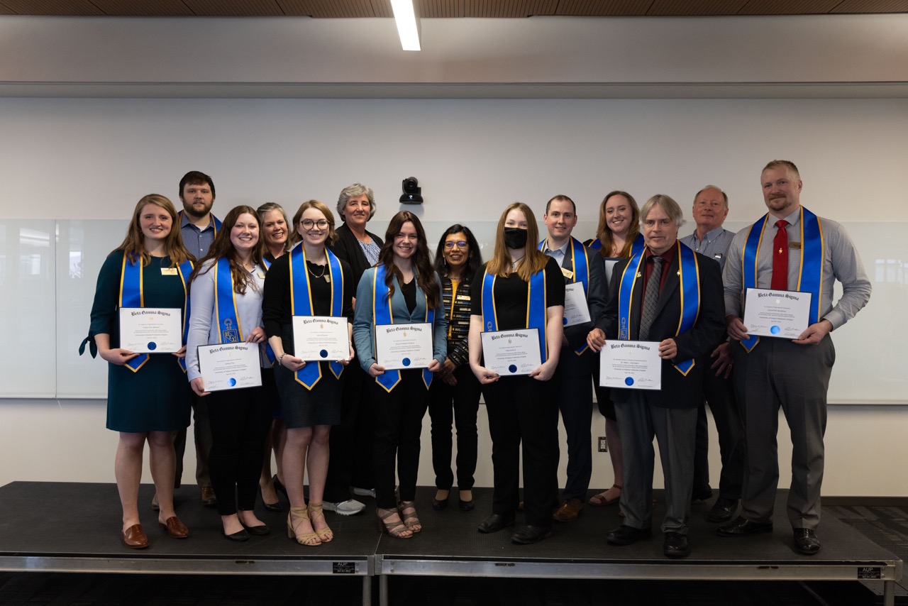 honor students wear blue and gold sashes, posing for a photo with certificates